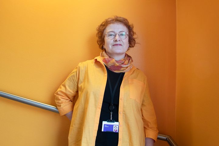 Päivi Vartiainen oranssin seinän edustalla TAMKin tiloissa.