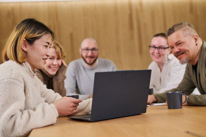 Aikuisopiskelijoita pöydän ja tietokoneen ääressä.