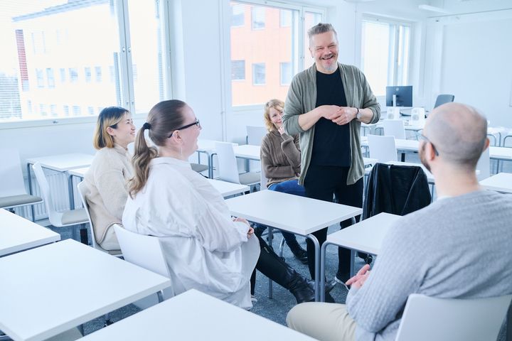 Kuvassa ihmisiä keskustelemassa luokkahuoneessa.
