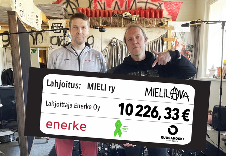 Kaksi miestä pitelee shekkiä, jolla lahjoitetaan 10 226,33 euroa MIELI ry:lle.