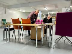 Rakennusmestari Teppo Humala ja huoltomies Jorma Ojanen ovat kumartuneet katsomaan laatikostoa.