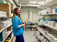 Sairaanhoitaja Sanni Vaskelainen seisoo tarvikevarastossa ja katsoo hyllyllä olevia tuotteita.