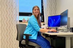 Sairaanhoitaja Sanni Vaskelainen hymyilee ja istuu työpöydän ääressä vastaanottohuoneessa.