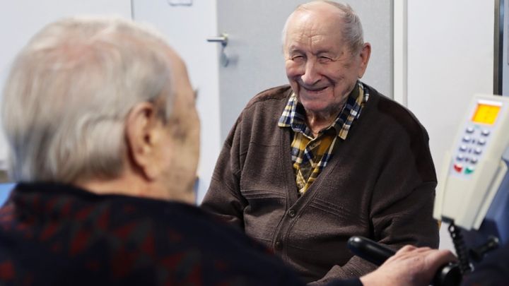 Kaksi ikääntynyttä, joista toinen nauraa kohti kameraa.