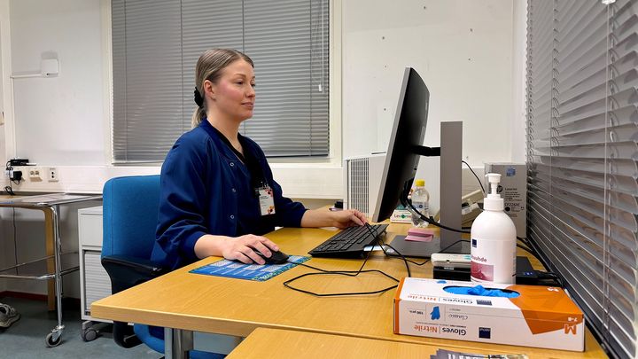 Farmaseutti Kaisa Hallinen istuu vastaanottohuoneessa työpöydän ääressä ja työskentelee tietokoneella.