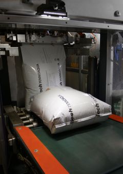 Suuria valkoisia kalanrehusäkkejä kulkee liukuhihnalla, säkeissä lukee Alltech Fennoaqua.