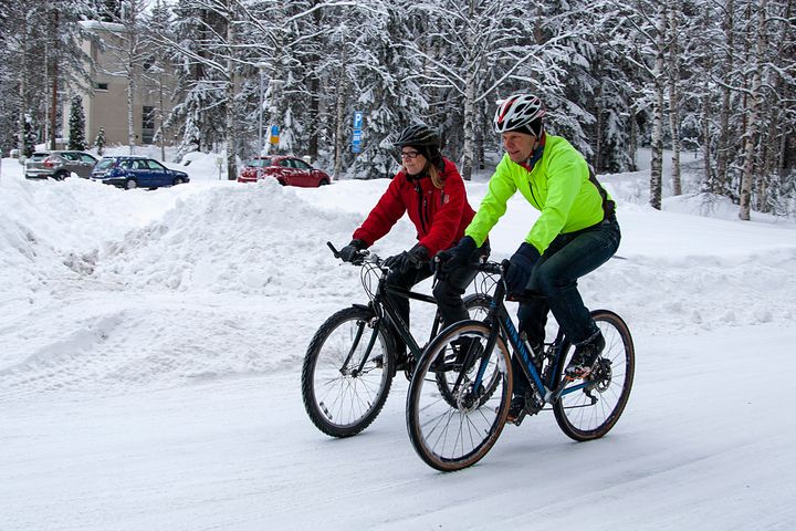 Kaksi pyöräilijää lumisella tiellä.