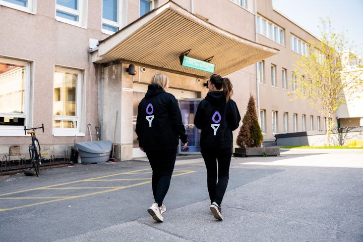 Kaksi mustiin Suomen Startup-yhteisön huppareihin pukeutunutta henkilöä kävelee Maria 01 startup-kampuksen pihalla.