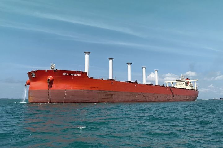 Punainen%20malminkuljetusalus%20Sea%20Zhoushan%20merell%E4%20ja%20kannella%20viisi%20sylinterim%E4ist%E4%20valkoista%20roottoripurjetta