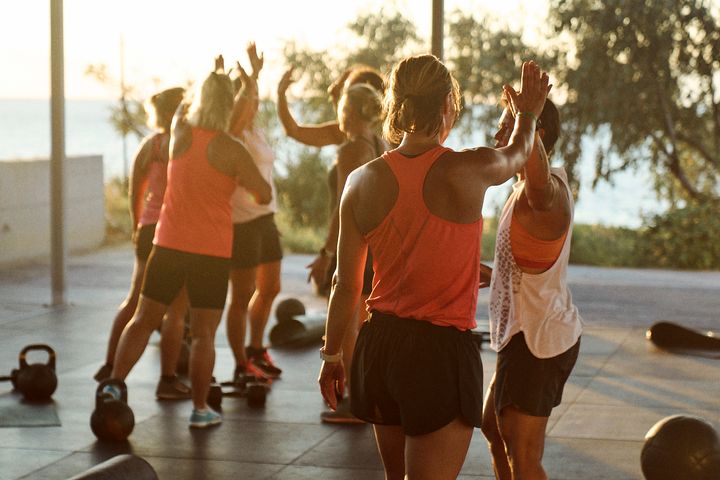 Ryhmä ihmisiä treenaa ulkona rannalla.
