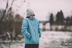 Yksinäinen poika seisoo talvisessa maisemassa.
