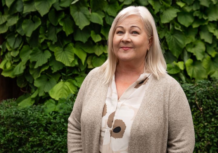 Humana Suomen toimitusjohtaja Leila Rutanen seisoo pensasaidan edessä.