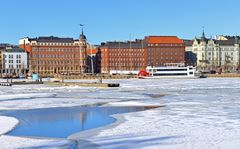 Vanhoja tiilikerrostaloja ja veneitä satamassa kauniina kevättalven päivänä.
