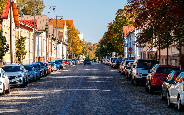 Värikkäitä puutaloja ja puita aurinkoisen kadun varrella Turussa