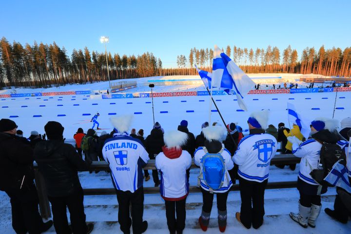 Leijonapaitoihin pukeutunut ja Suomen lippuja heiluttava ryhmä Kontiolahden ampumahiihtostadionin A-katsomossa.