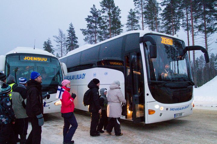 Linja-autokuljetukset tuovat ja noutavat kisavieraat ampumahiihtostadionin pääportin tuntumasta.