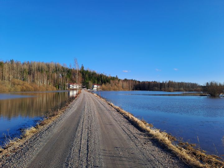 Keväinen hiekkatie, jonka molemmilla puolilla tulvavettä.