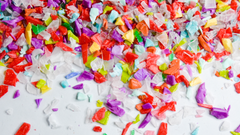 Värikkäitä muovinpalasia valkoista taustaa vasten.