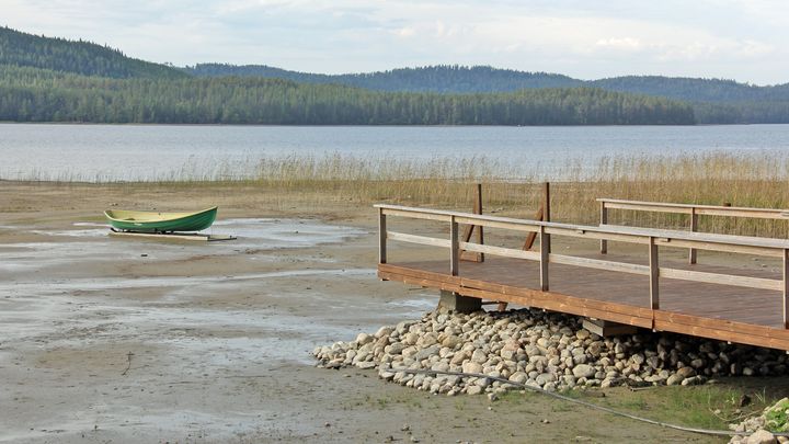Laituri ja vene ovat jääneet kuivalle maalle, kun vedenpinta on laskenut huomattavasti.