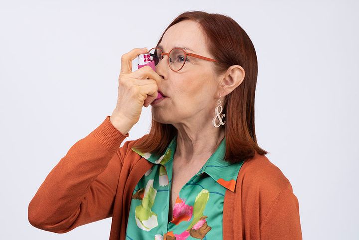 Nainen vetää henkeen astmalääkettä inhalaattorilla.