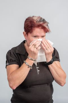 Nainen niistää nenäliinaan.