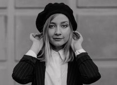 Pianisti Anni Kiviniemi pitää molemmilla käsillä hatustaan kiinni mustavalkoisessa kuvassa.