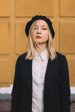 Anni Kiviniemi kuvattuna keltaisen seinän edustalla.