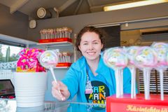 Valkoinen, hymyilevä, naispuolinen kioskityöntekijä Särkänniemen T-paidassa ojentaa isoa tikkaria kohti kameraa.