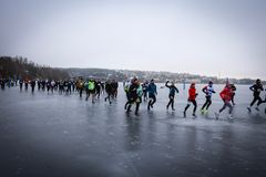 Ihmisiä juoksemassa liukkaalla, jäätyneellä tiellä harmaassa säässä.
