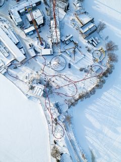 Ilmakuva lumisesta huvipuistoalueesta, jossa näkyy Särkänniemen Konect-huvilaite ja muita laitteita talvella.