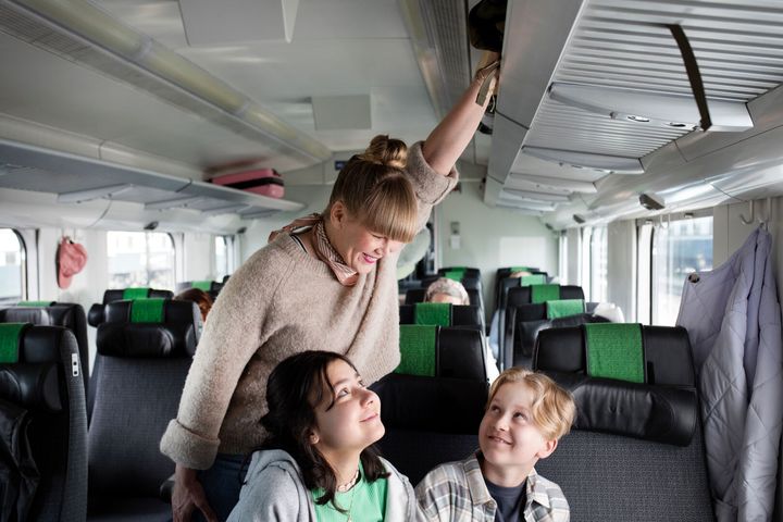 Nainen ja kaksi teini-ikäistä junamatkustajaa aloittamassa matkaa.