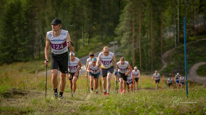 Moni käyttää tunkkausrinteessä apunaan sauvoja. Kuva: Nuuksion Tonni 2025, kuvaaja Poppis Suomela.