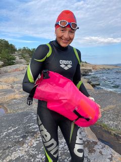 Sanna Hokkanen huilaa avovesiuinnin lomassa ja ottaa uimarin poijusta evästä.