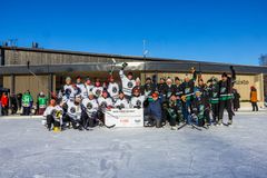 Ryhmä kuvassa on jääkiekkojoukkueita, jotka juhlivat Save Pond Hockey Tampereen turnauksen jälkeen aurinkoisena päivänä ulkojäällä.