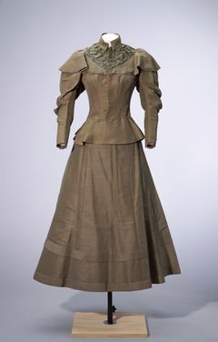 Promenaddräkt, 1890-tal, Tammerfors historiska museer.  Denna amerikanska fritidsdress från 1890-talet har en timglasformad silhuett, fårbogsärmar och med korsett insnörd midja. Dräktens kjol som är gjord av tjockt siden är kortare än vanligt har förstärkt fåll. Dräkten har eventuellt också använts för cykling.  Foto: Reetta Lepistö / Tammerfors historiska museer.