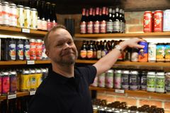 Ravintolan olutkylmiössä ravintolapäällikkö esittelee tuotteita, hyllyillä pullo-oluita.