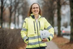 Eeva-Riitta Tuomisen puolivartalokuva. Hänellä on yllään keltainen heijastava työmaatakki ja hän pitelee suojakypärää kädessään vartaloaan vasten. Katse on hymyilevä ja suoraan eteen. Taustalla syksyinen puistomaisema, lehdet ovat jo pudonneet puista.