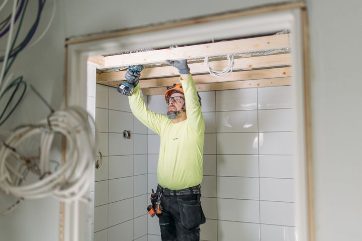 Remonttipartion työntekijä remontoimassa kylpyhuoneen kattoa.