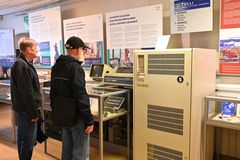 Kaksi henkilöä katselee vanhoja tietokoneita museossa näyttelytilassa.