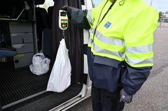 Tullin työntekijä punnitsee muovipussissa olevaa tavaraa käsivaa'alla.
