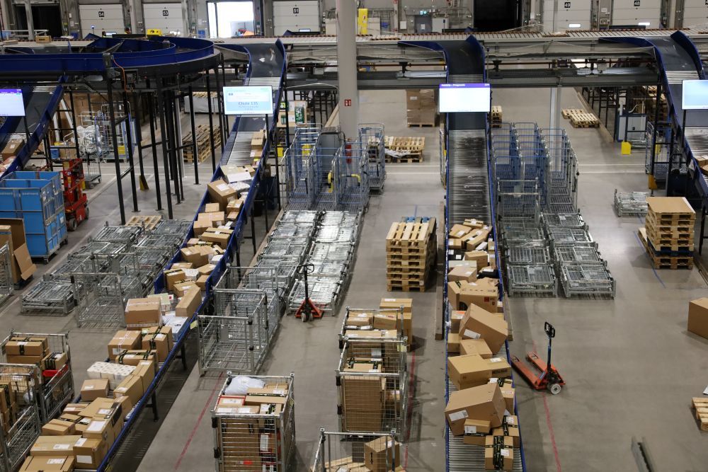 Kuva isosta avarasta tilasta, jossa liukuhihnoja ja lukuisia paketteja.