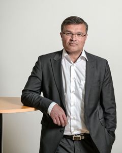 A man in a suit standing next to a round table.