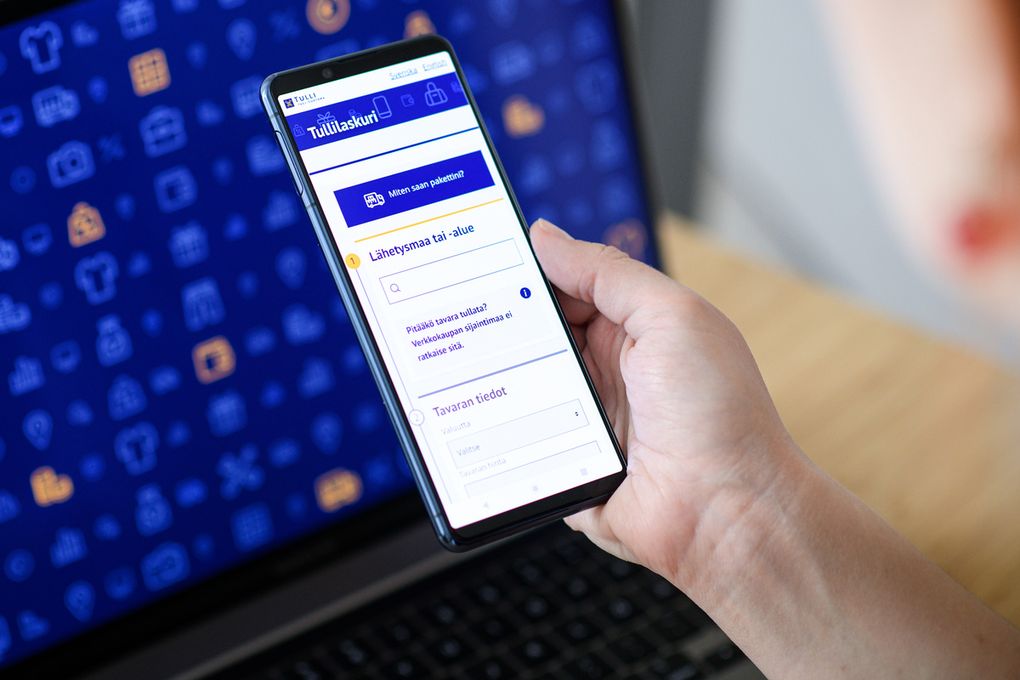 Käsi pitelee älypuhelinta, jossa on auki Tullilaskuri-sovellus.