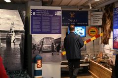 Näkymä Tullimuseon teemanäyttelystä, jossa kävijä tutustuu erilaisiin esineisiin ja infotauluihin.