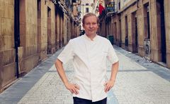 Henkilö valkoisessa kokkitakissa seisoo tyhjän kadun keskellä.