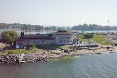 Rakennus meren rannalla, jossa on pyöreä ravintolasali. Näkymä on kesäinen ja taustalla näkyy purjeveneitä ja saaristoa.