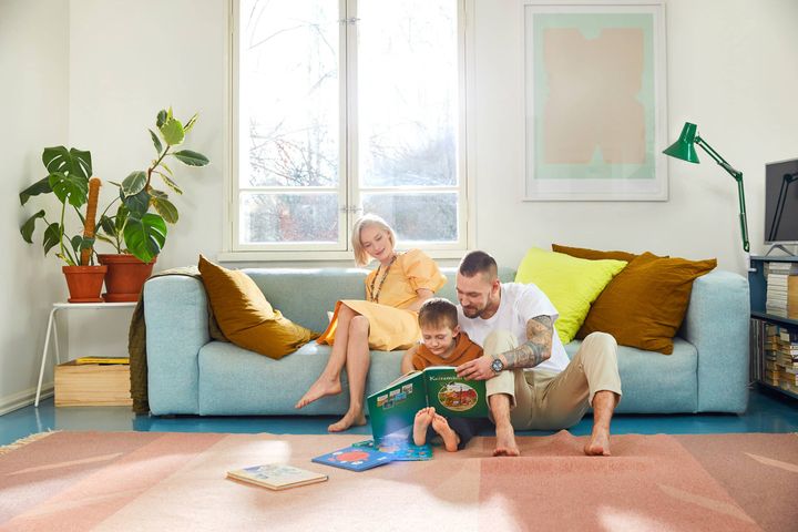 Perhe istuu sohvalla ja tutkii kirjaa.