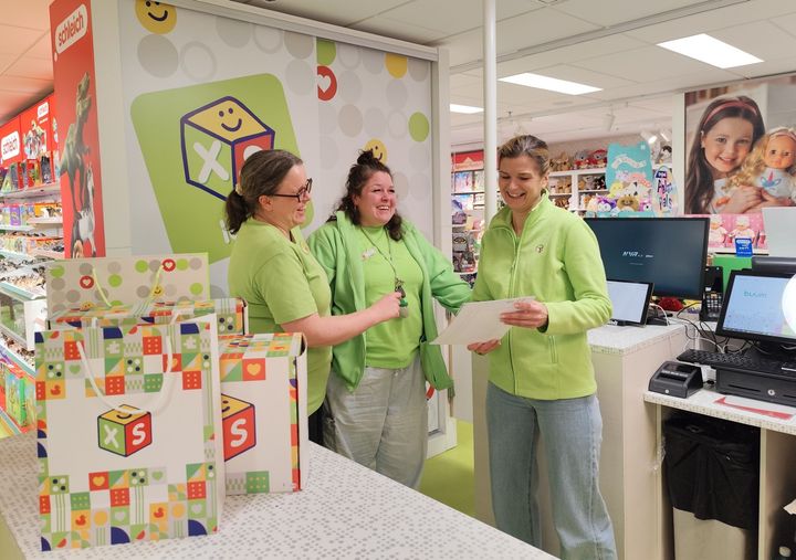 XS Lelujen vihreään pukeutuneet myyjät keskustelevat ILOA-toimintaperiaatteista.