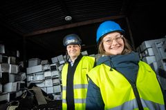 Olli Alanen ja Maija Hirsmäki keltaisissa huomioliiveissä ja suojakypärissä kierrätyslaitoksella