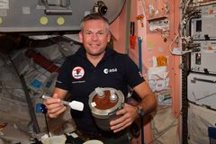 Astronautti Andreas Mogensen ottamassa suklaamoussea jälkiruoaksi avaruusasemalla.